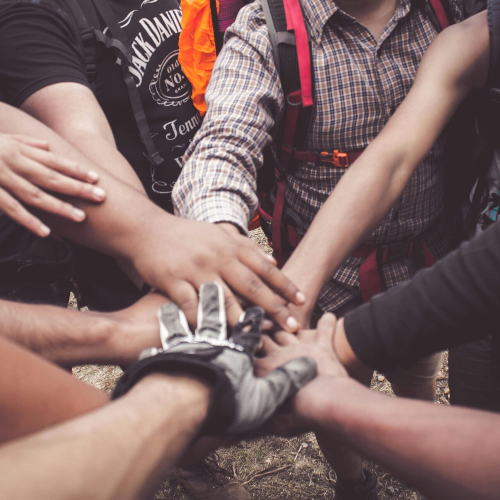 A group of diverse individuals join hands for teamwork in West Java, Indonesia.