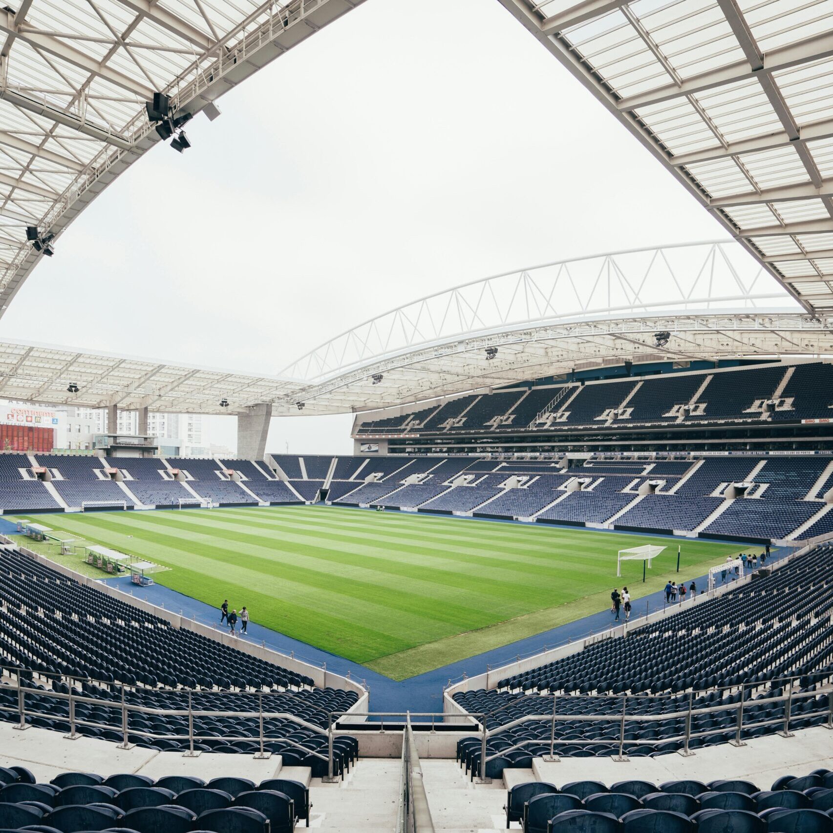 Wide-angle view of a contemporary stadium featuring empty bleachers and a well-maintained grass field, perfect for various sports.