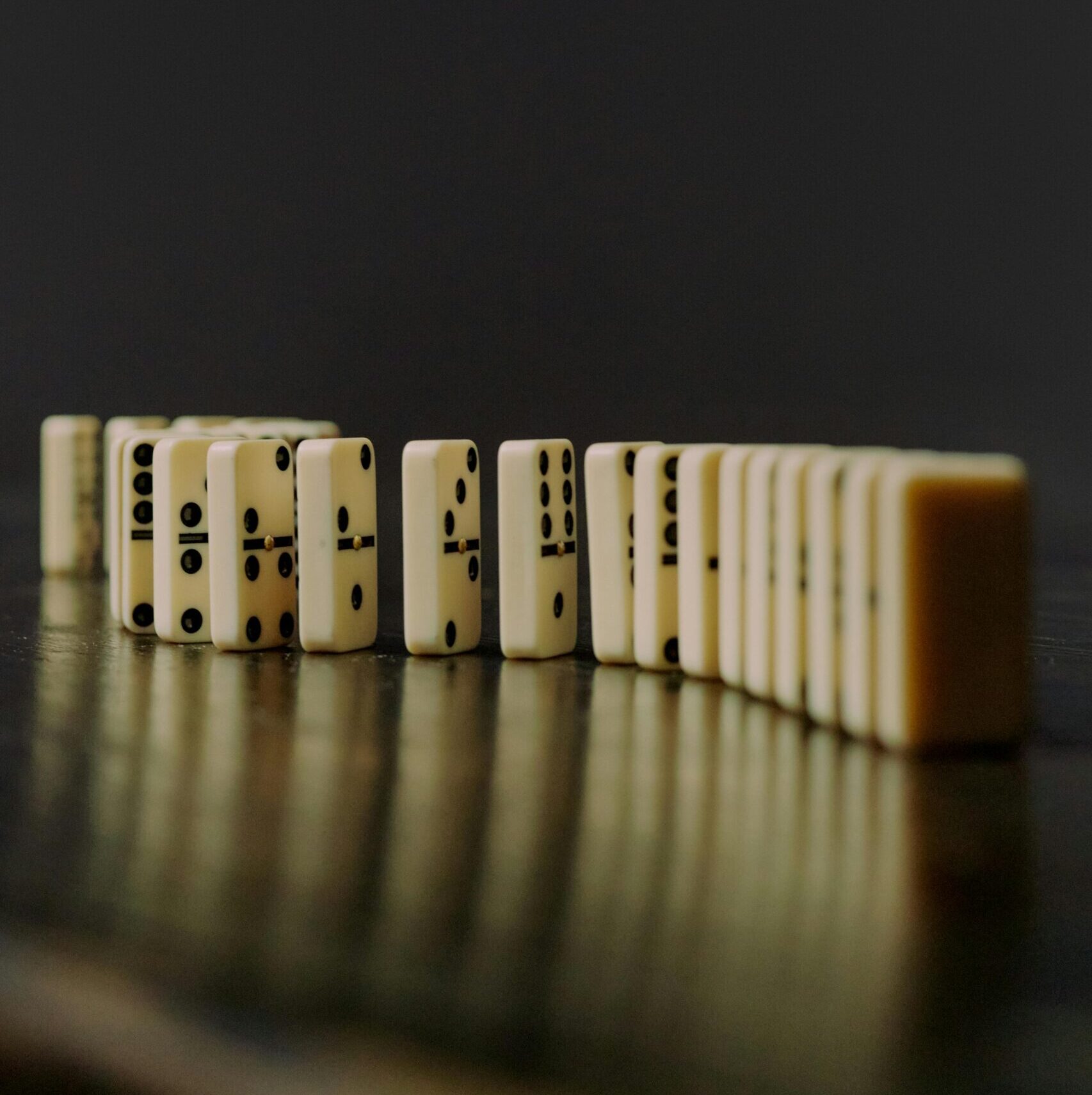 Domino blocks lined up on a reflective surface, symbolizing order and balance.